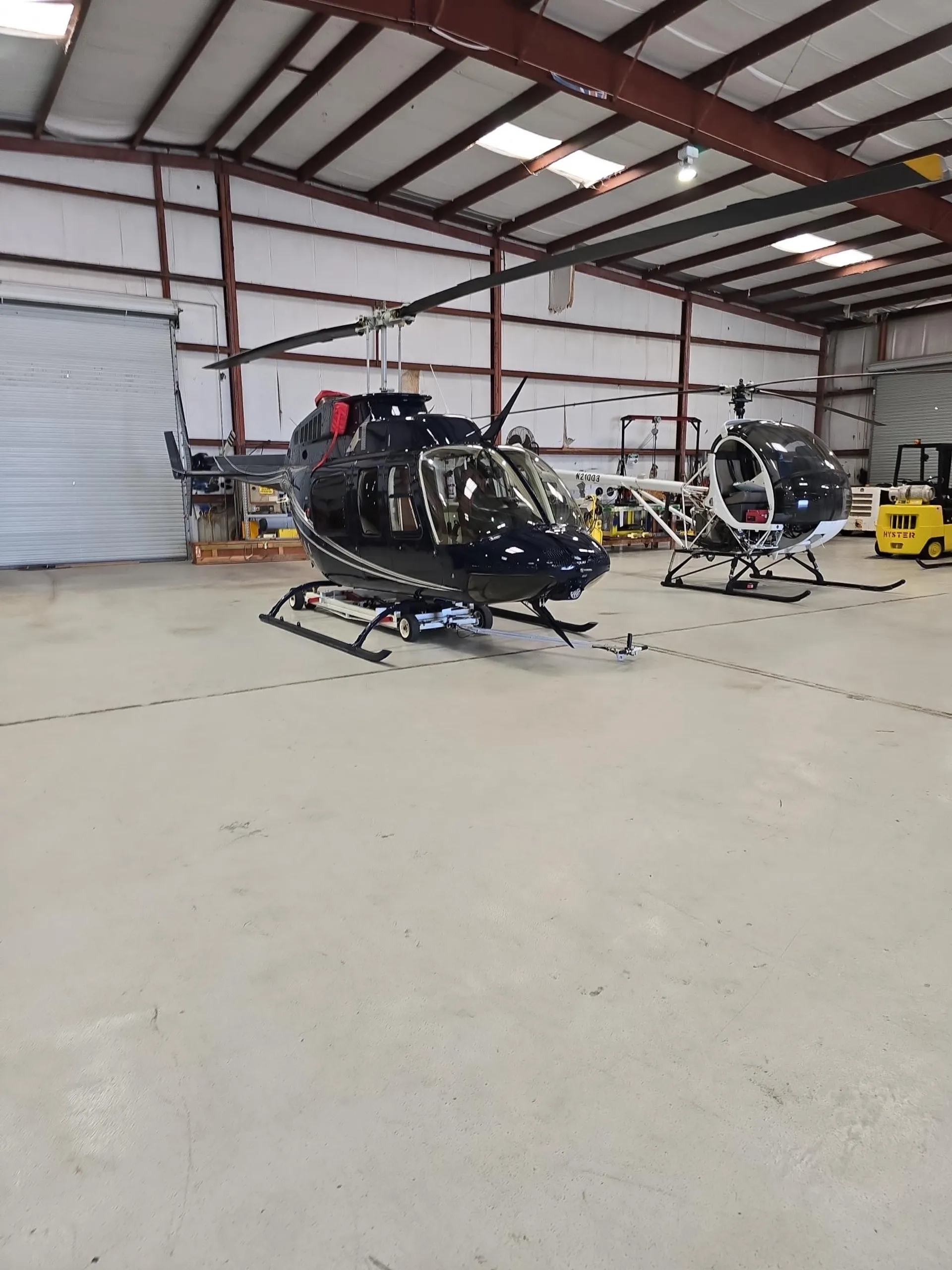 Aviation technician performing helicopter maintenance on dark blue aircraft at USATS